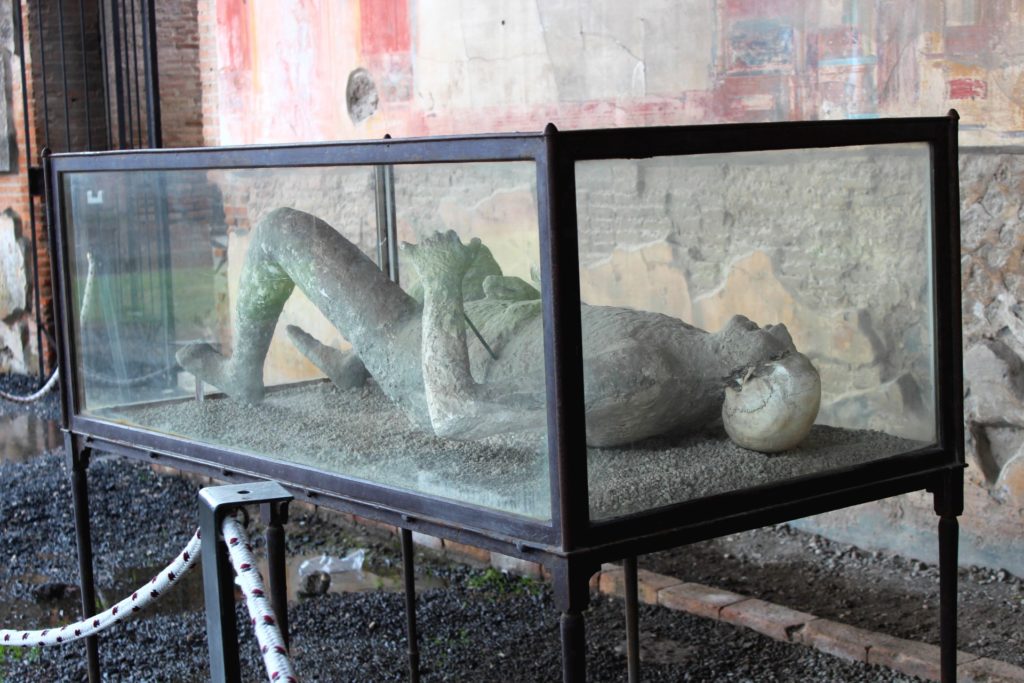 one of the bodies of pompeii in a glass box