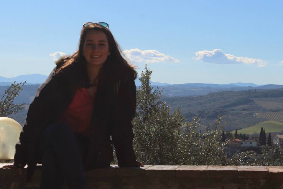 girl sitting at a view point of san gimignano with tuscany countryside on the background