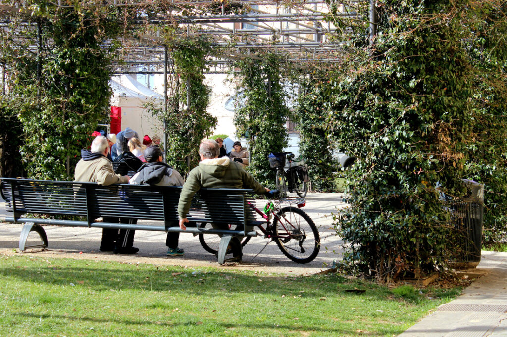 three elderly locals sitting on a bench in a park in pisa